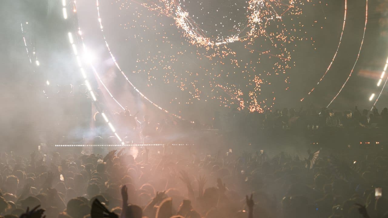 Vue sur une salle de concert plongée dans la pénombre, scène illuminée au fond.