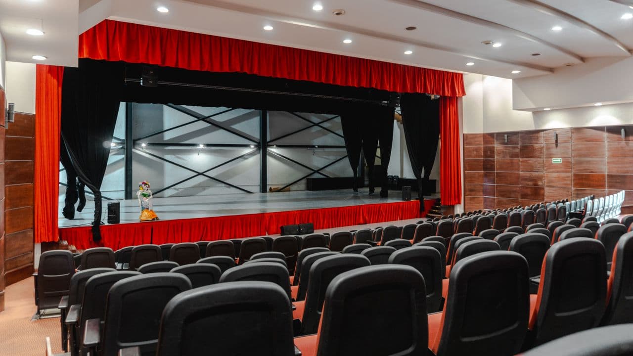 Projecteurs de théâtre dirigés vers une scène plongée dans la pénombre.